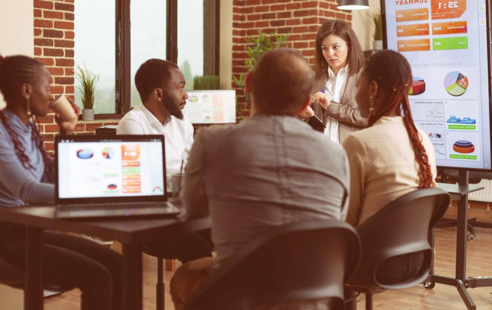 Conference room setup with presentation screen displaying budget charts and data visualizations